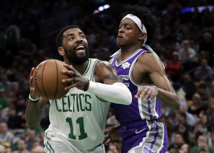 Kyrie Irving of the Celtics drives against Sacramento's De'Aaron Fox in the first half Thursday night at Boston. Irving had 31 points, 12 assists and 10 rebounds in Boston's 126-120 win.