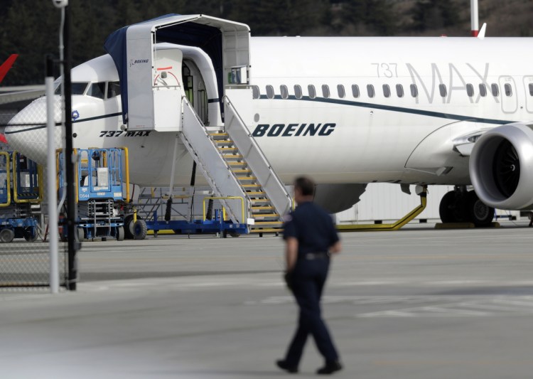 A worker walks next to a Boeing 737 MAX 8 airplane parked at Boeing Field in Seattle on Thursday. 