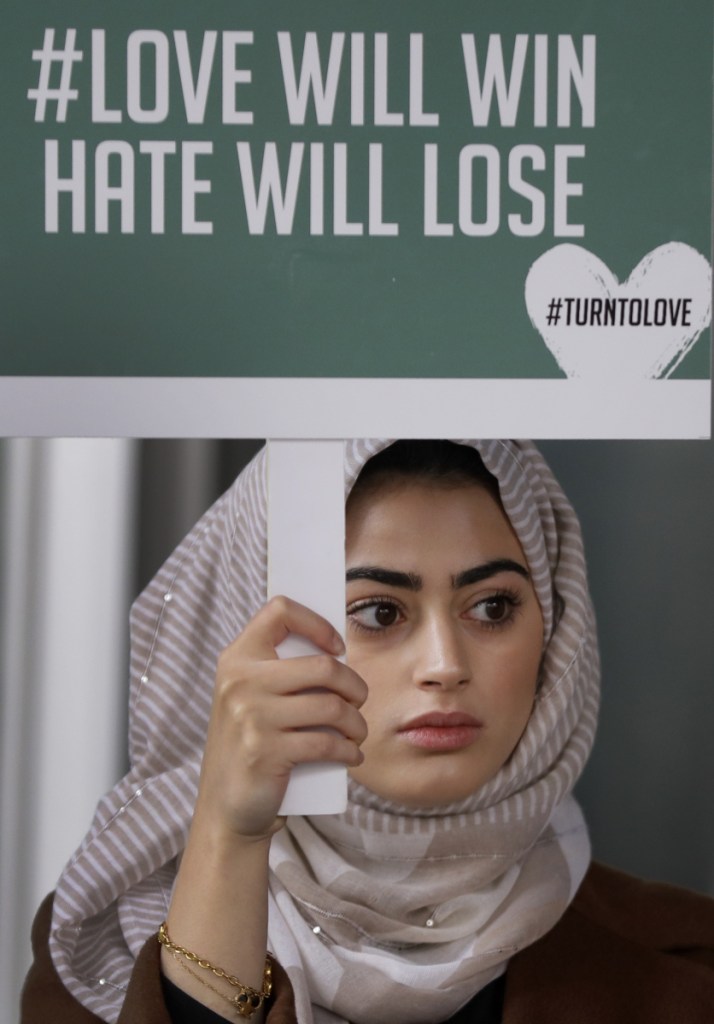 A demonstrator holds a banner from a multi-faith group, "Turn to Love," during a vigil at New Zealand House in London on Friday following the deadly attacks on two mosques in Christchurch.