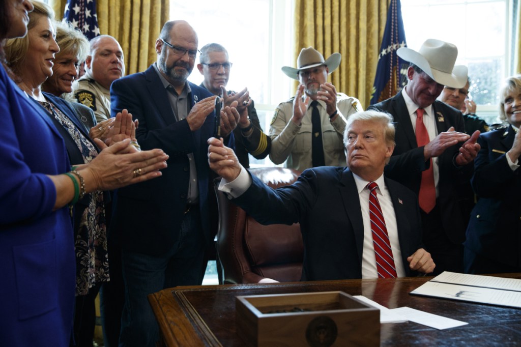 President Trump hands out a pen after signing the first veto of his presidency Friday in the Oval Office of the White House. His veto overruled a congressional resolution opposing his declaration of a national emergency at the U.S.-Mexico border.