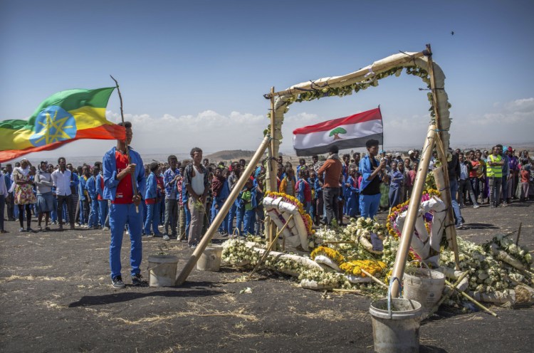 Students stand next to floral tributes Friday at the scene where the Ethiopian Airlines Boeing 737 Max 8 crashed shortly after takeoff Sunday, killing all 157 on board. The students walked an hour and a half from their school to pay their respects.