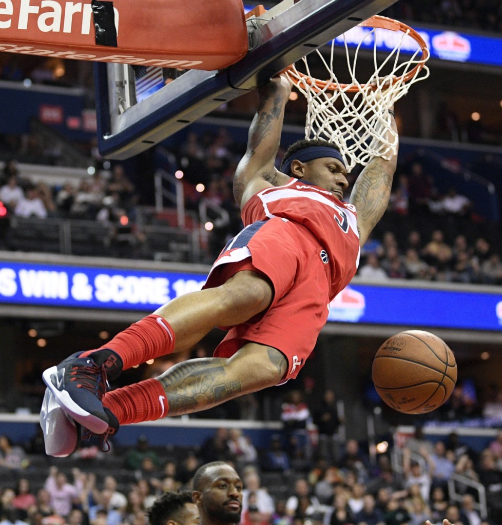 Bradley Beal of the Washington Wizards hangs on the rim after a dunk Friday night. Beal scored 40 points but it wasn't enough to prevent the Charlotte Hornets from coming away with a 116-110 victory.