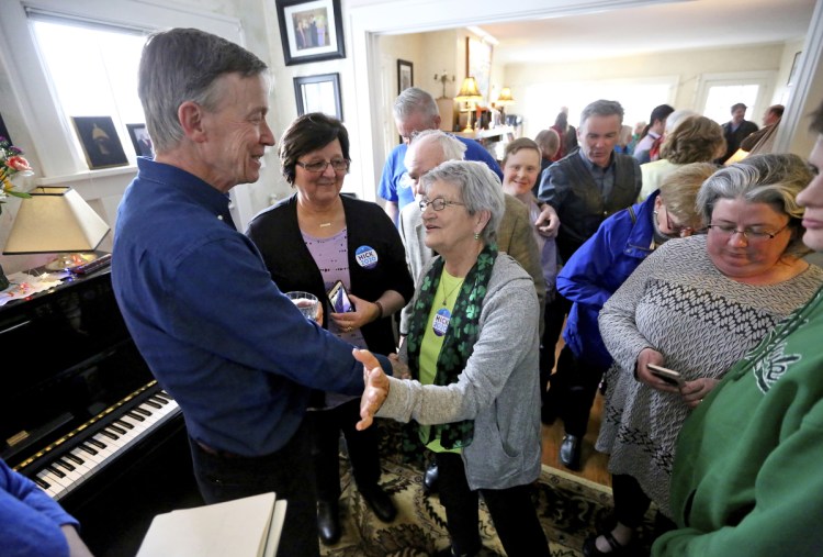 Former Colorado Gov. John Hickenlooper greets attendees during a visit to a Dubuque, Iowa, home earlier this month. As a teenager, Hickenlooper volunteered to work in Maine.