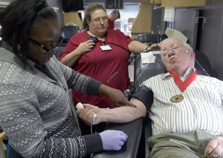 Red Cross phlebotomists Meika Reed, left, Laura Landry draw blood on Wednesday from Jack Schrader in a Red Cross van at the Augusta branch of Kennebec Savings Bank.