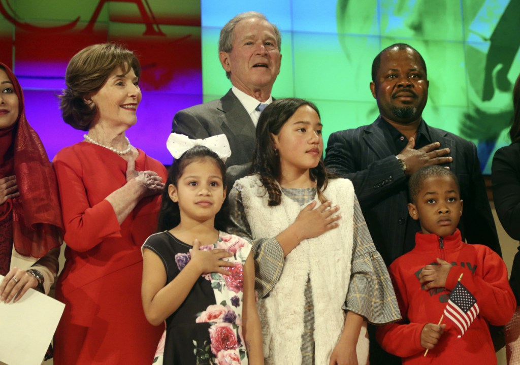 Former President George W. Bush and former first lady Laura Bush recite the pledge of allegiance Monday with new U.S. citizens, including Felix Odeh, top right, of Nigeria, during a naturalization ceremony at the George W. Bush Presidential Center in Dallas. Forty-nine people became American citizens at the ceremony.