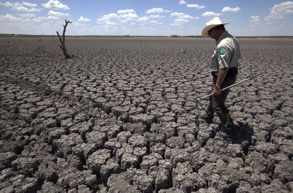 A Texas State Park police officer walks across the parched lake bed of O.C. Fisher Lake, in San Angelo, Texas, in 2011. The impacts of record-breaking heat and years of low rainfall can be felt years after a dry spell passes.