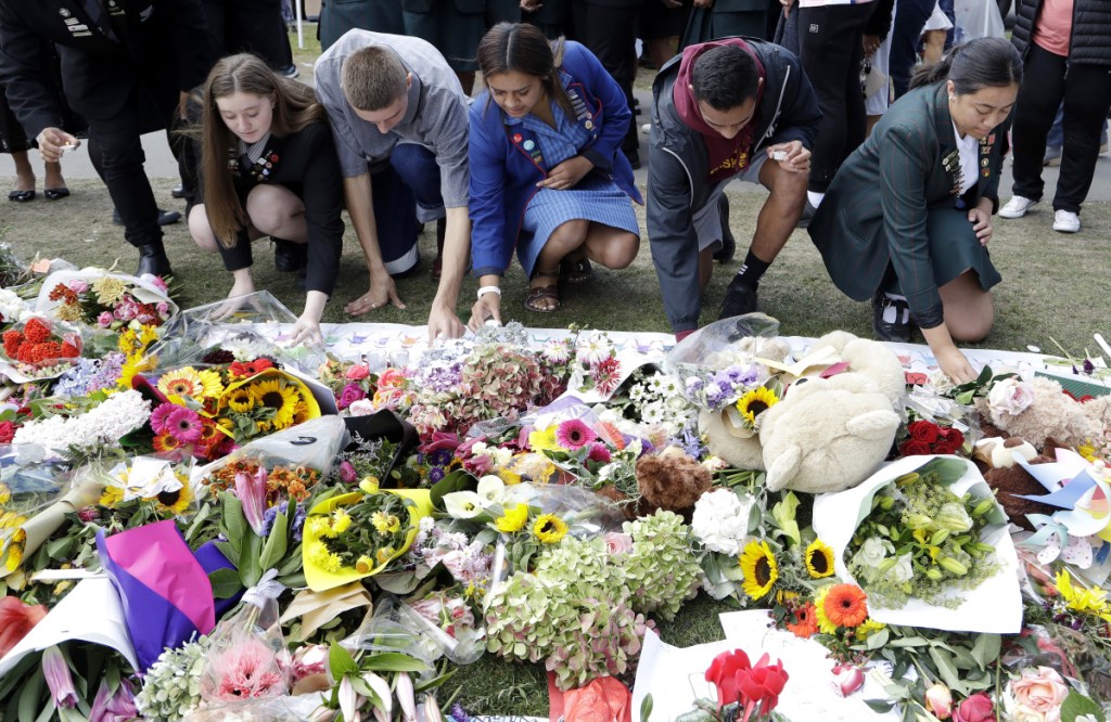 Students from Christchurch high schools light candles at a tribute at the Botanical Gardens in Christchurch, New Zealand, on Tuesday as relatives and friends of the 50 victims from Friday's shootings began to bury the dead.