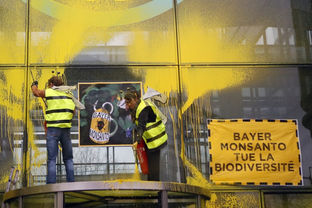 French activists of Attac spray-paint the Paris headquarters of Bayer AG last week to protest its production of pesticides. Bayer is battling dozens of lawsuits over the weed killer Roundup, made by its American subsidiary Monsanto. "Bayer Monsanto Kills Biodiversity," the placard reads.