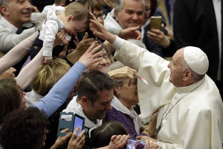 Pope Francis blesses a child while greeting members of a youth tourism group in the Paul VI Audience Hall at the Vatican on Friday.