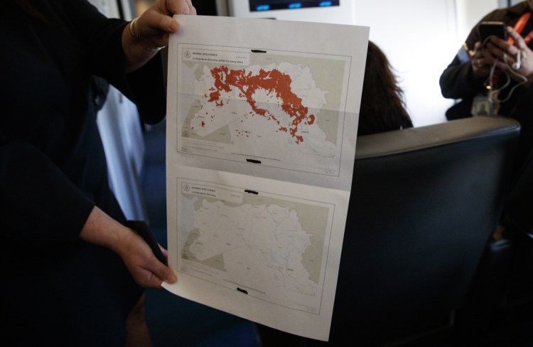 White House press secretary Sarah Sanders holds a map of Syria in the press cabin on Air Force One on Friday after the presidential jet landed  in West Palm Beach, Fla. Sanders said the Islamic State's "territorial caliphate has been eliminated in Syria."