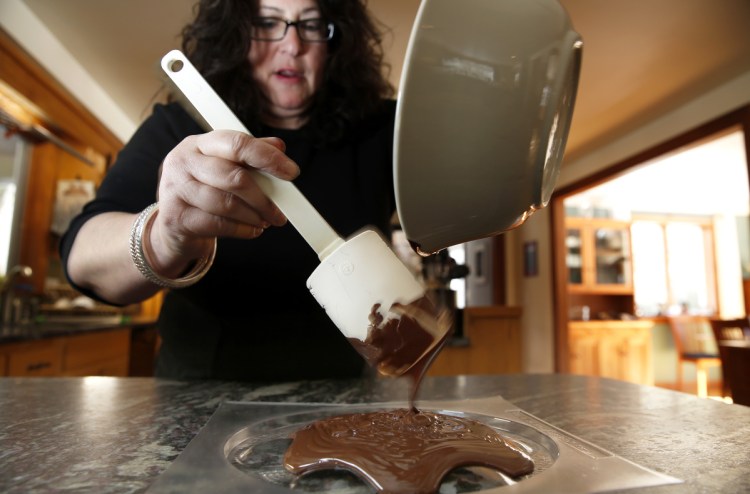 Rabbi Laura Boenisch of B'nai Portland pours chocolate into a Seder plate mold at her Falmouth home. Boenisch started a chocolate Seder some 10 years ago, at first just for kids, but now lots of adults come, too. 