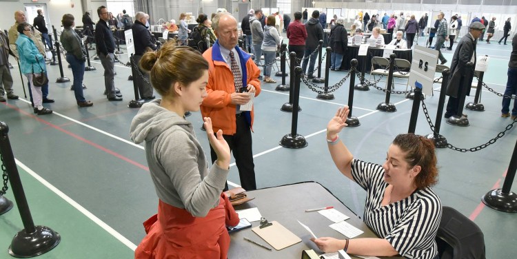 Colby College student Alexandria Fraize, left, swears the information she gave election clerk Allison Brochu is accurate before voting at Thomas College on Tuesday, Nov. 6, 2018. City Solicitor Bill Lee observes. An effort to disqualify the votes of Colby College students in the November election has been dismissed by the Maine Supreme Judicial Court.
