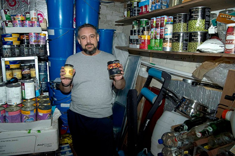 Melvin Burton holds up stored provisions in his garden shed in Littleport, Cambridgeshire, England on Friday.