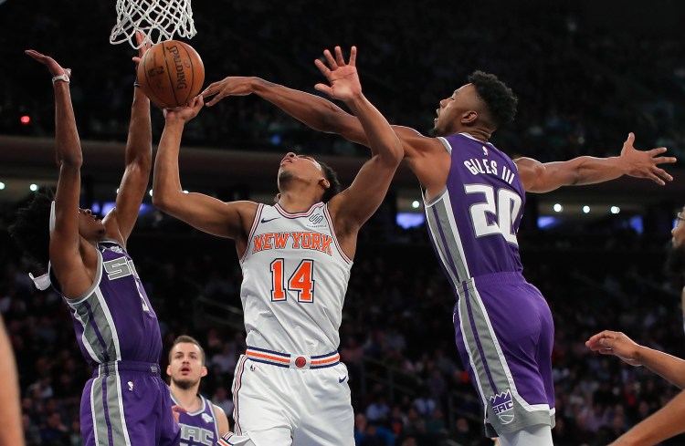 New York Knicks guard Allonzo Trier puts up a shot against Sacramento Kings forward Harry Giles III, right, and guard De'Aaron Fox during the Kings' 102-94 win Saturday in New York.
