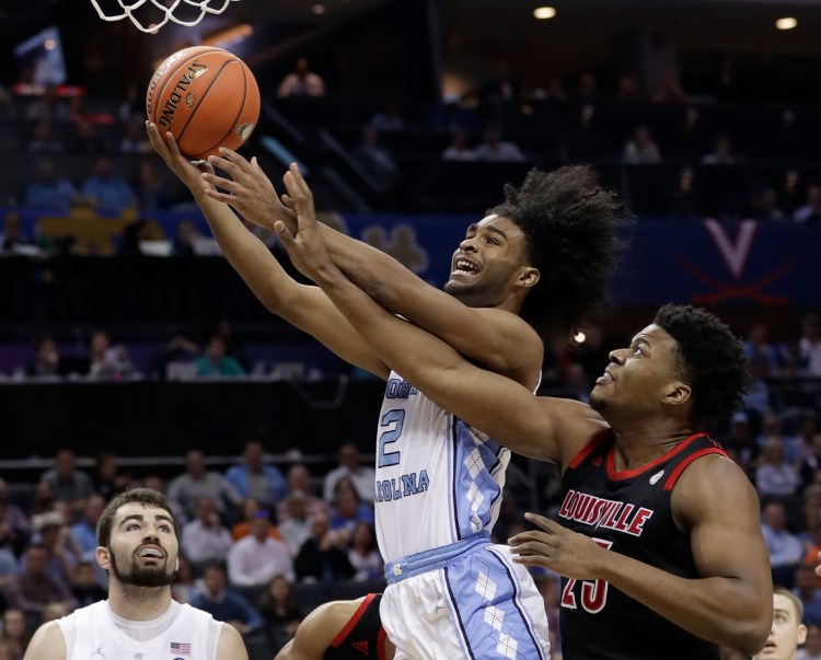 North Carolina's Coby White (2) drives past Louisville's Steven Enoch (23) during the first half of an NCAA college basketball game in the Atlantic Coast Conference tournament in Charlotte, N.C., Thursday, March 14, 2019. (AP Photo/Chuck Burton)