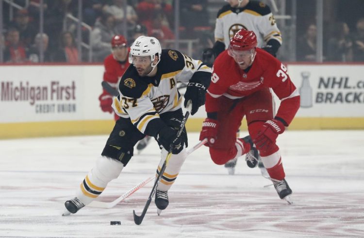 Boston's Patrice Bergeron controls the puck as Anthony Mantha of the Red Wings chases during the first period Sunday night in Detroit. Mantha scored three goals in a 6-3 victory.