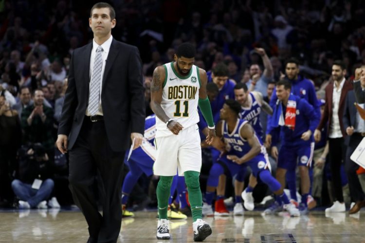 Boston Celtics' Kyrie Irving, center, and coach Brad Stevens, left,  walk the court for a timeout after Jimmy Butler scored a basket during the second half of an NBA basketball game Wednesday, March 20, 2019, in Philadelphia. Philadelphia won 118-115. (AP Photo/Matt Slocum)