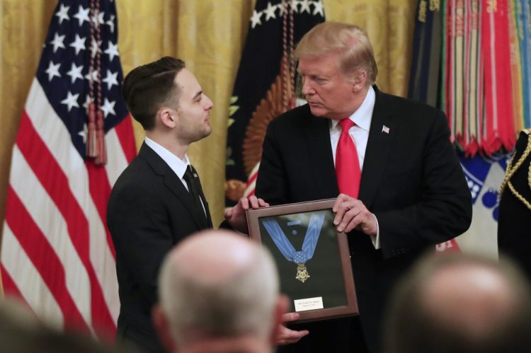 Trevor Oliver accepts the Medal of Honor from President Trump, presented Wednesday to his father, Army Staff Sgt. Travis Atkins, for his gallantry in Iraq in June 2007.