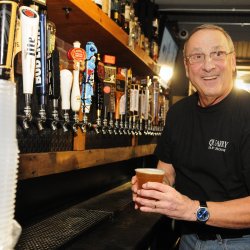 Gov. Paul LePage carries a beer he just poured to a customer during a celebrity bartender fundraiser for the Travis Mills Foundation in 2017 at the Quarry Tap Room in Hallowell. 