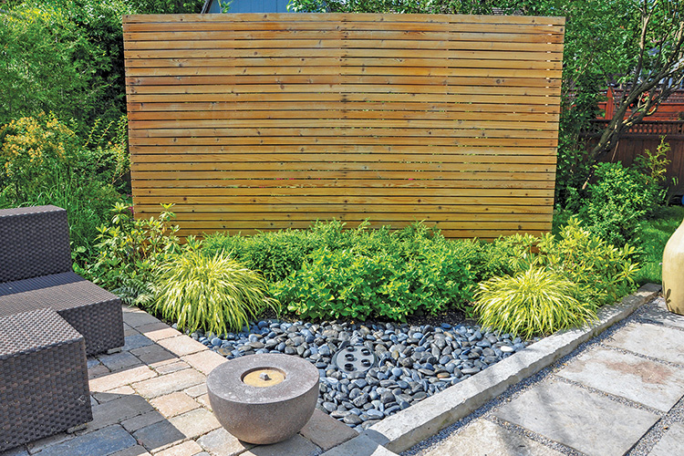 Beach pebbles, flagstone, brick landscape pavers and simple plantings provide ample texture in this small backyard with a Japanese-inspired look. 