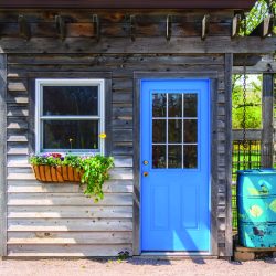 A garden shed with a blue door that is used for more than storing lawn care equipment.