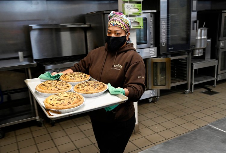 Christina Nop of Lake & Co. carries a tray of mushroom and Gruyere quiches from the oven to a cooling rack while working in the kitchen Tuesday at Fork Food Lab in Portland.