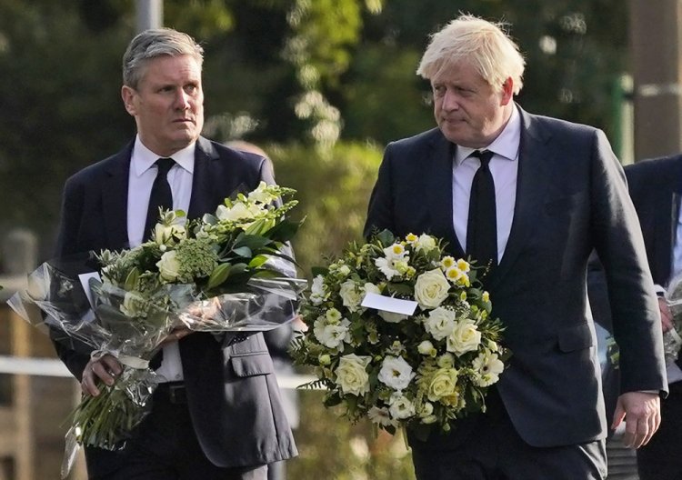 British Prime Minister Boris Johnson, right, and leader of the Labour Party Keir Starmer carry flowers as they arrive at the scene where a member of Parliament was stabbed Friday, in Leigh-on-Sea, Essex,  England.

