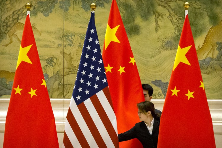 Chinese staffers adjust U.S. and Chinese flags before the opening session of trade negotiations between U.S. and Chinese trade representatives at the Diaoyutai State Guesthouse in Beijing in February 2019. 