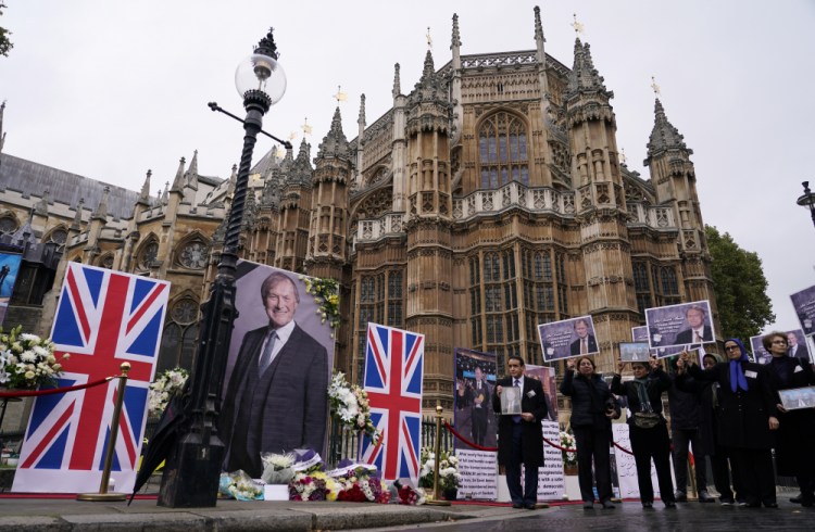 Members of the Anglo-Iranian communities and supporters of the National Council of Resistance of Iran hold a memorial service for British MP David Amess outside the Houses of Parliament in London, Monday, Oct. 18, 2021. 