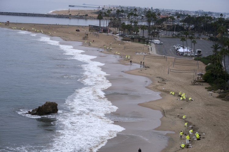 Workers in protective suits clean the contaminated beach in Corona Del Mar on Oct. 7 after an oil spill in Newport Beach, Calif. 