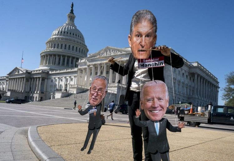 A climate change demonstrator mocks Sen. Joe Manchin, D-W.Va., who has blocked President Biden's domestic agenda, at the Capitol in Washington on Wednesday. 