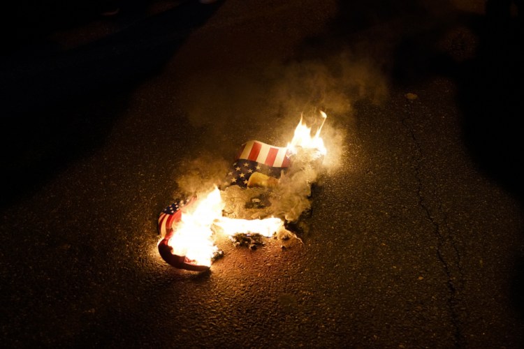 A sign that counter-protesters lit on fire burns after supporters of President Trump held pro-Trump marches on Nov. 14, 2020, in Washington. 