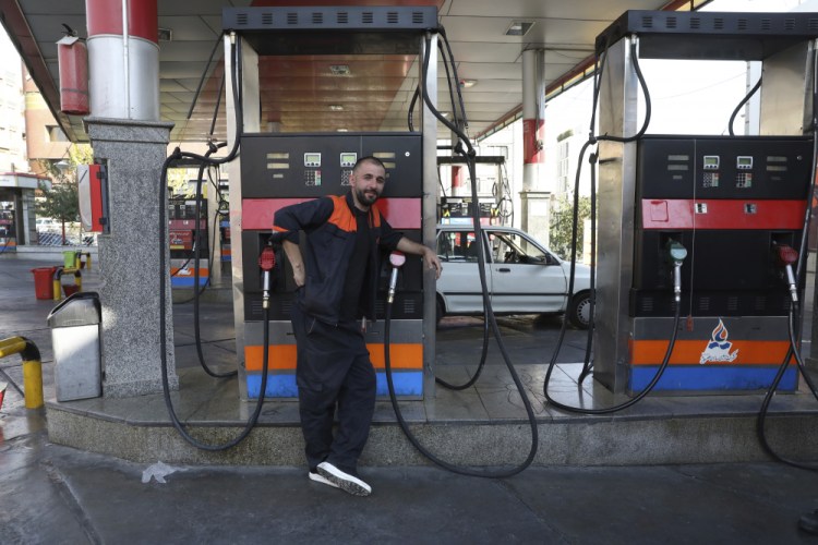 A worker leans against a gasoline pump that has been turned off at a gas station in Tehran, Iran, on Tuesday.

