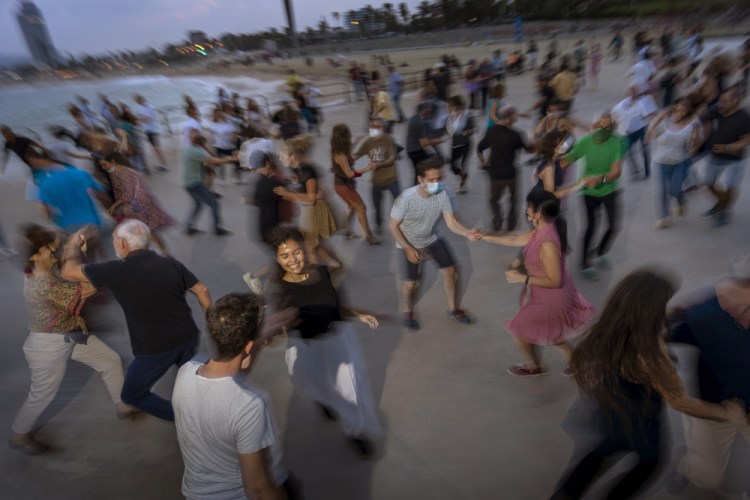 People dance on a promenade facing the Mediterranean as the sun sets at a beach in Barcelona,Spain. Every Sunday swing lovers gather to dance in front of the sea organized by the swing dance school. 