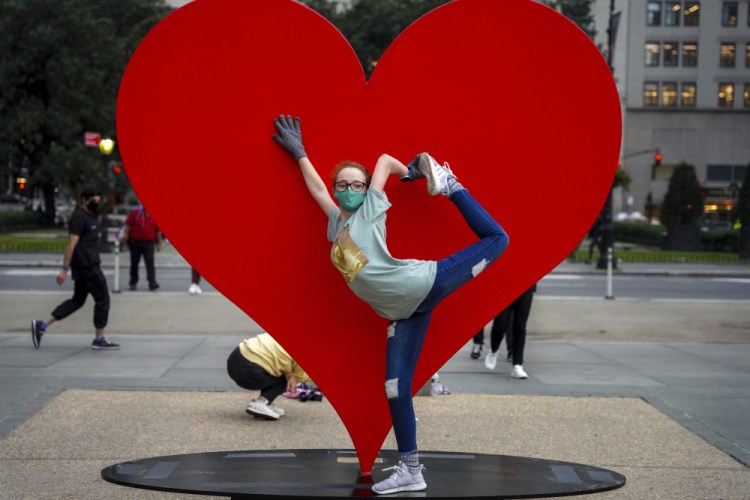 A teenager poses last week in front of "The Hero Monument" sculpture Monday in Manhattan's Grand Army Plaza in New York. The sculpture, dedicated to health care workers around the world,  has been taken down – an apparent casualty of confusion and red tape.. (AP Photo/Dieu-Nalio Chery, File)