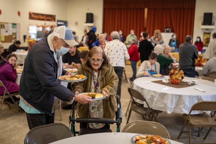 Ted Walogorsky helps Betty Durbetaki set her meal down at their table Thursday at the Most Holy Trinity Church in Saco. Dozens of volunteers served hundreds of meals.