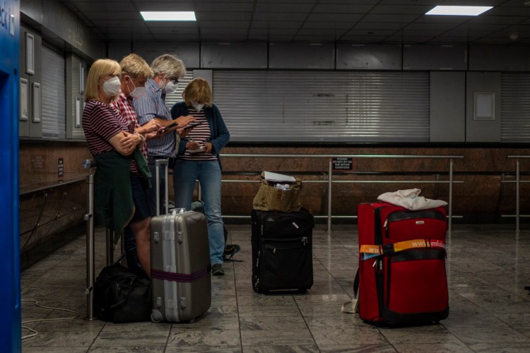 Passenger check their phones at Johannesburg's OR Tambo's airport, Monday Nov. 29, 2021. The World Health Organisation urged countries around the world not to impose flight bans on southern African nations due to concern over the new omicron variant. (AP Photo/Jerome Delay)