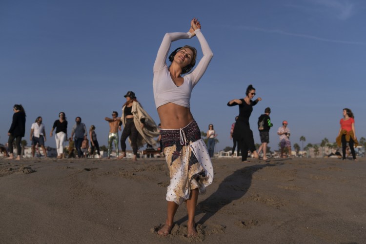 With music playing through wireless headphones, Chase Beckerman, a 37-year-old mother of two, and other participants dance on the beach during a weekly event hosted by Ecstatic Dance LA on Venice Beach in Los Angeles on Sept. 29.

