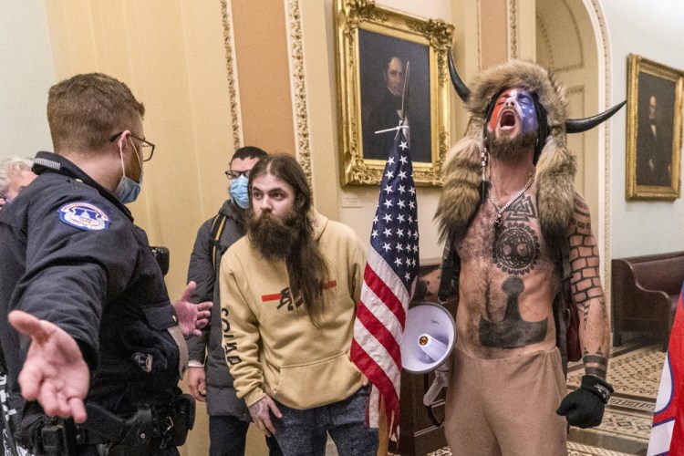 Jacob Chansley, right, wearing a fur hat, shouts during the Capitol riot in Washington on Jan. 6, 2021. He was sentenced Wednesday to 41 months in prison. 