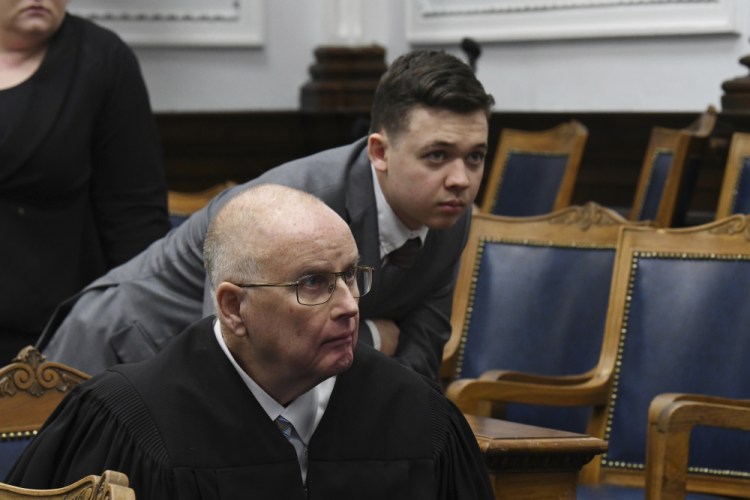 Judge Bruce Schroeder and Kyle Rittenhouse look at a video screen as attorneys for both sides argue about a video during Rittenhouse's trial at the Kenosha County Courthouse in Kenosha, Wis., on Friday. Rittenhouse is accused of killing two people and wounding a third during a protest over police brutality in Kenosha, last year. 