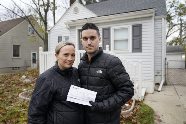 Nicole and Simon Obarto hold a lead and copper analysis of water from the Oakland County Health Division as they stand outside their home in Royal Oak, Mich., this month. The couple had their water line tested for lead and the results were high enough to have the lead service line replaced. 