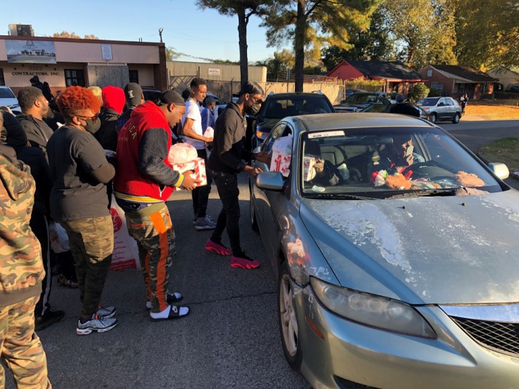 Friends of slain rapper Young Dolph distribute Thanksgiving turkeys outside St. James Missionary Baptist Church on Friday in Memphis, Tenn. The hip-hop artist and music label owner had helped organize the event, but he was fatally shot Wednesday inside a Memphis bakery. Police were searching for suspects Friday. (AP Photo/Adrian Sainz)
