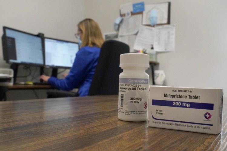 A nurse practitioner works in a Fairview, Ill.,  Planned Parenthood clinic where she confers via teleconference with patients seeking self-managed abortions. Containers of the medication used to end an early pregnancy sit on a table nearby.