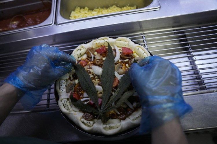 A cannabis leaf is put on a pizza at a restaurant in Bangkok, Thailand. The Pizza Company, a Thai major fast food chain, has been promoting its "Crazy Happy Pizza" this month, an under-the-radar product topped with a cannabis leaf. It’s legal but won’t get you high.