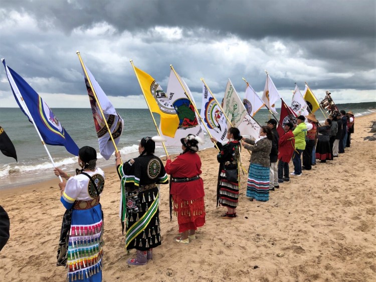 Native American women veterans participate in a flag ceremony on Omaha Beach in France in 2018 to commemorate their peoples’ participation in the D-Day battle of World War II.
