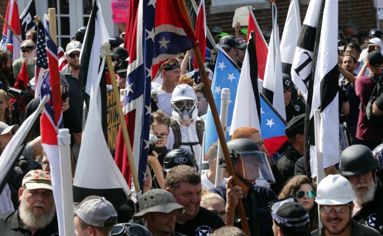 White nationalist demonstrators walk into the entrance of Lee Park surrounded by counter demonstrators in Charlottesville, Va., on Aug. 12, 2017.  A jury began deliberations Friday in a civil trial of white nationalists accused of conspiring to commit racially motivated violence at that deadly “Unite the Right” rally. 