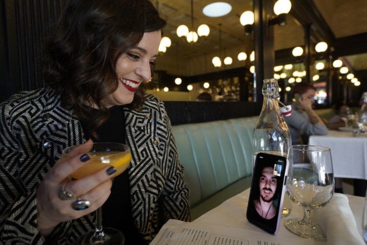 Erin Tridle holds a video chat with her boyfriend Jordan Commarrieu living in Paris from their favorite French restaurant "Petit Trois" in Los Angeles on Friday. Travel restrictions that have separated couples and relatives living in different countries are about to end. 