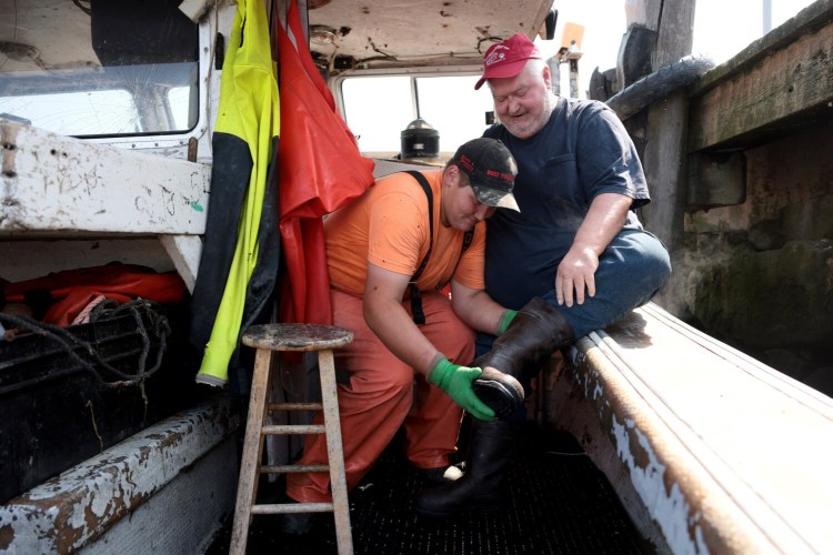 Michael Grimshaw’s son, Roderick, helped him to put his boots on, a task that has become more difficult for Michael since he suffered a stroke last winter. Michael is among the last commercial lobstermen on Long Island Sound.