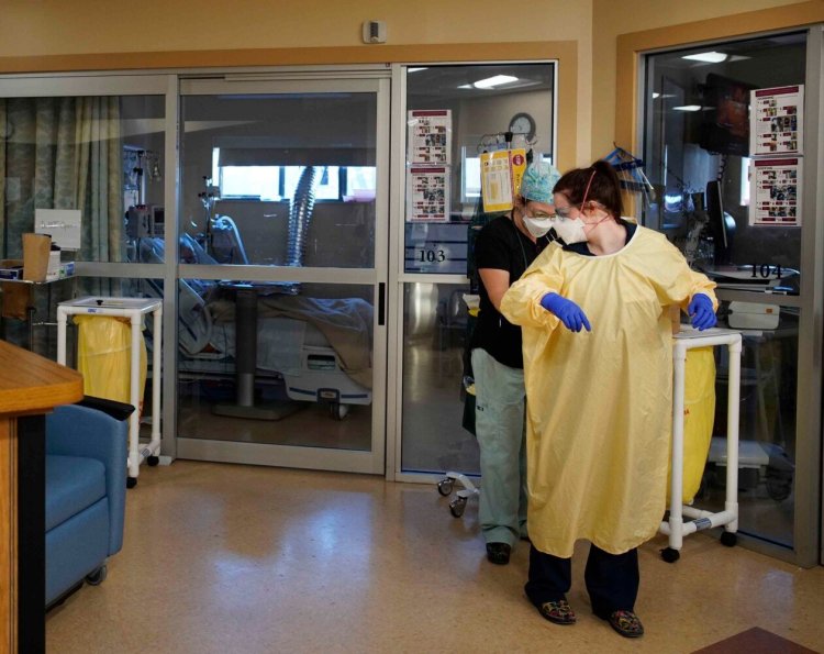 Ashley Cude helps Liz Michaud put on a precaution gown on in the Special Care Unit at Stephens Memorial Hospital in Norway. The two registered nurses care for patients suffering from acute COVID-19 symptoms.