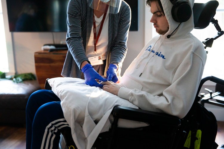 Jack Weeks, 17, a senior at Casco Bay High School, works with an occupational therapist at his home in Gorham in December. He was paralyzed in a diving accident in June 2020, and diagnosed with incomplete quadriplegia.